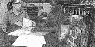 Two women discussing papers at desk.