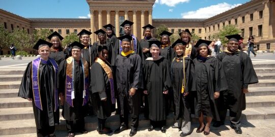 Graduates posing in front of historic building.
