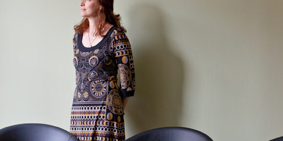Woman standing near a table, looking away.