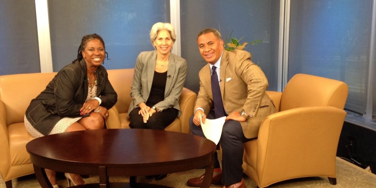 Three people sitting on a couch in an office.