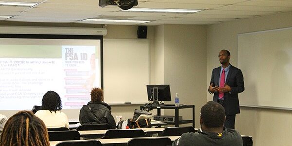 A man in suit and tie standing at the front of an auditorium.