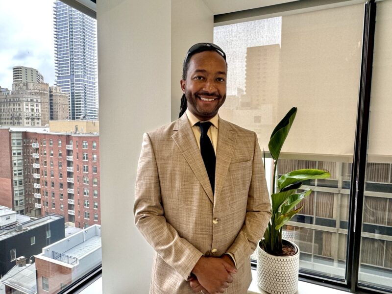 A man in a suit standing next to a window.