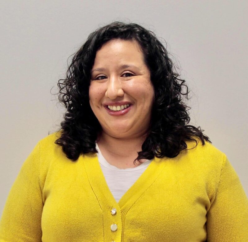 A woman in yellow sweater smiling for the camera.