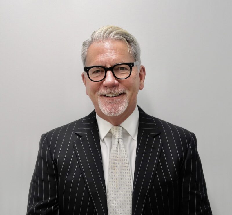A man in a suit and tie standing next to a wall.
