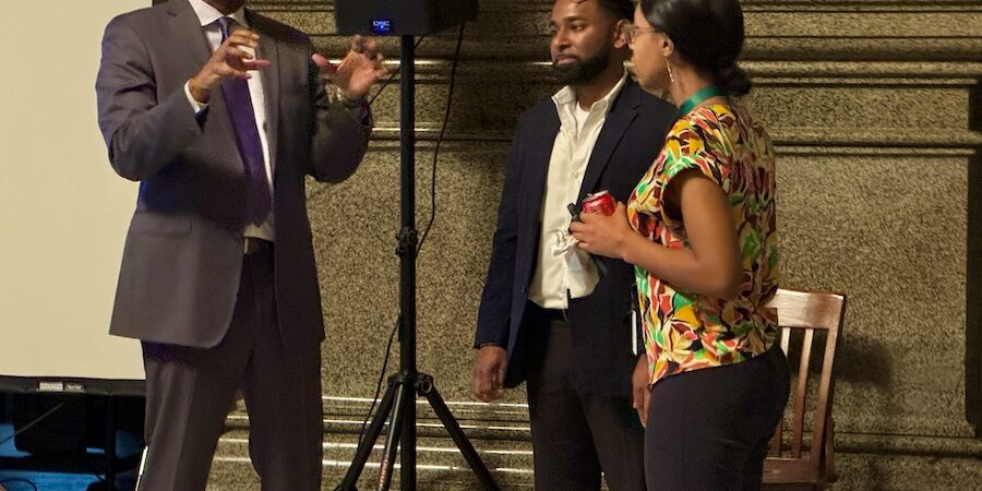 A man and two women standing in front of an audience.