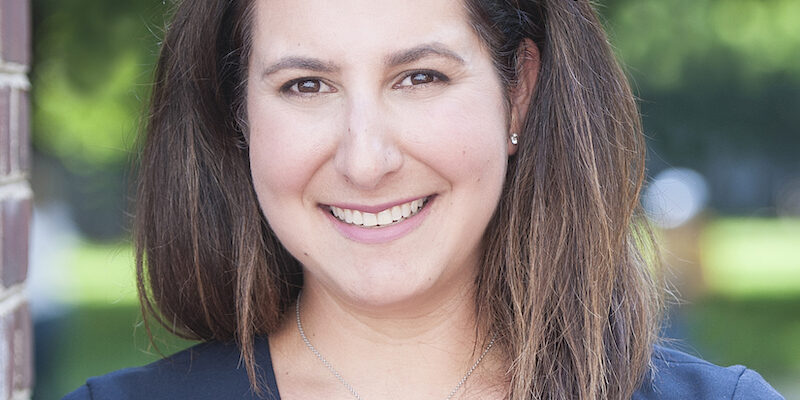 A woman standing in front of a brick wall.