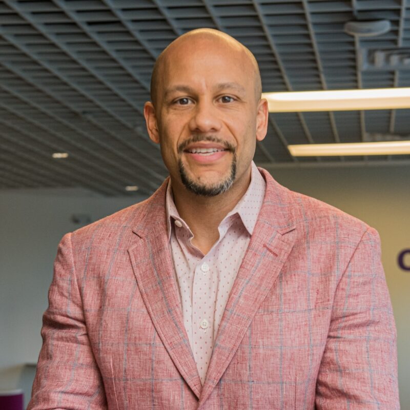 A man in a pink suit standing next to a wall.