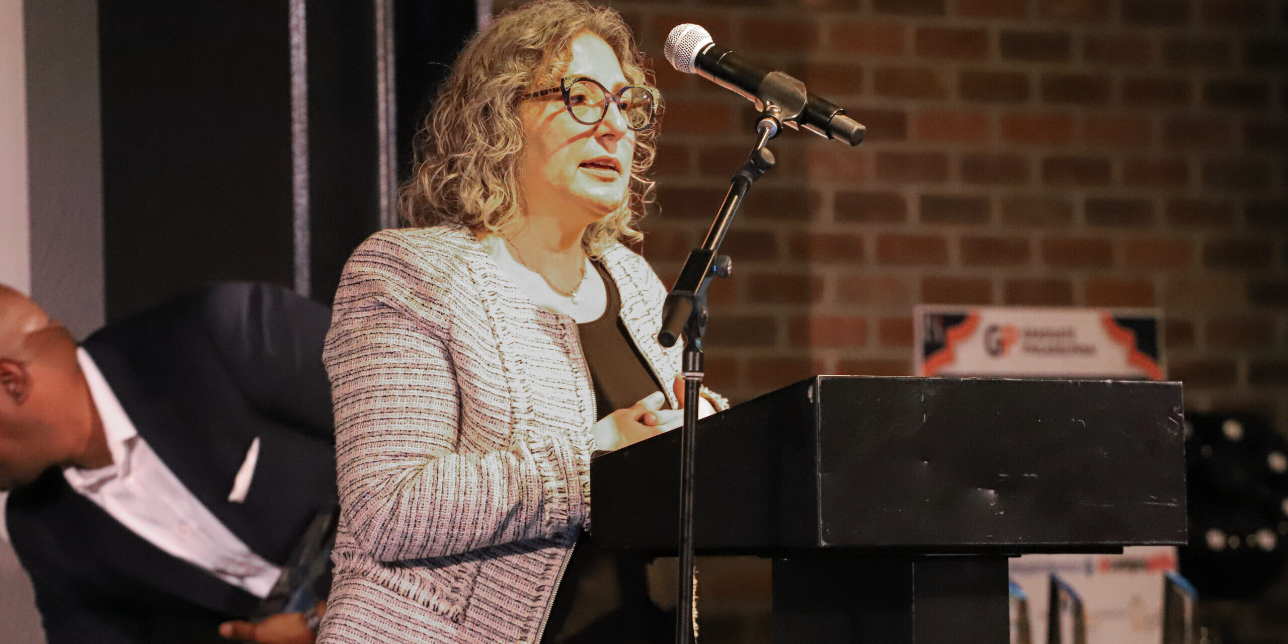 A woman standing at a podium speaking to an audience.