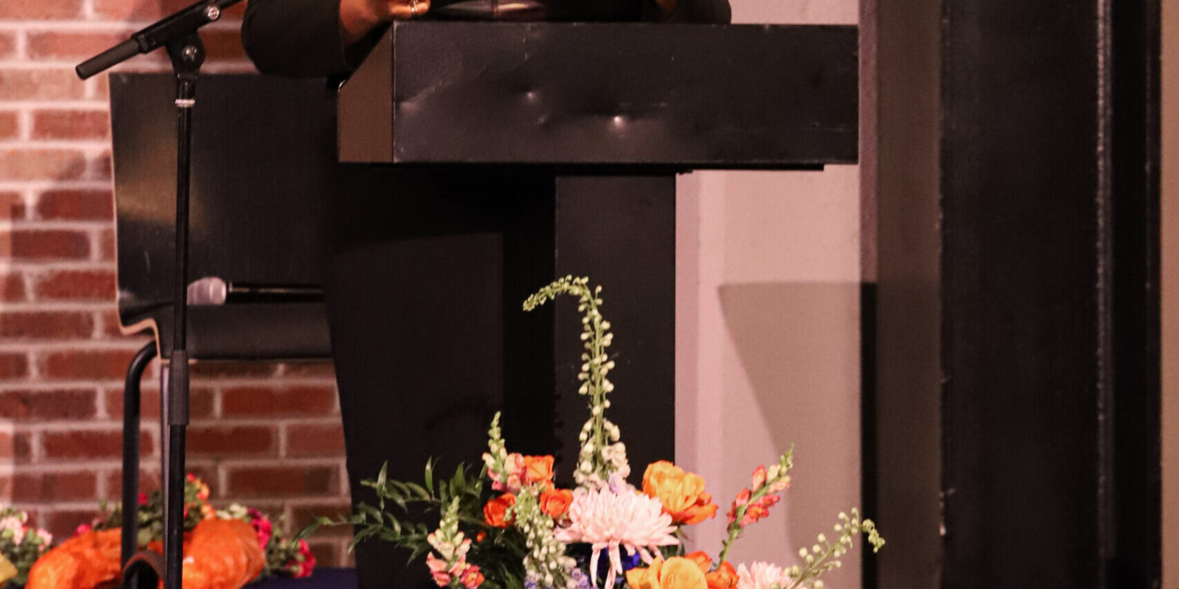 A woman standing at a podium with flowers in front of her.