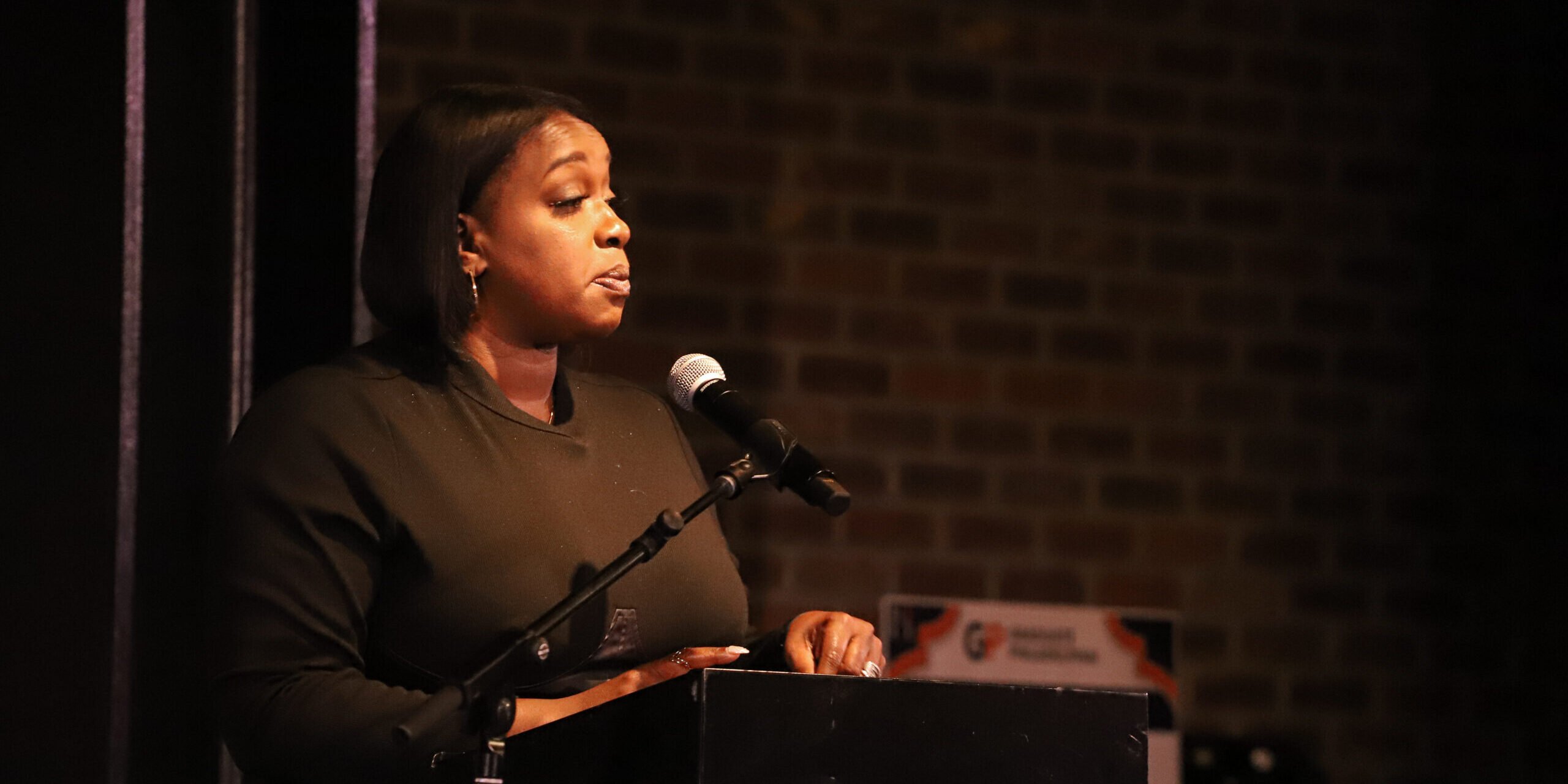 A woman standing at a podium with a microphone.