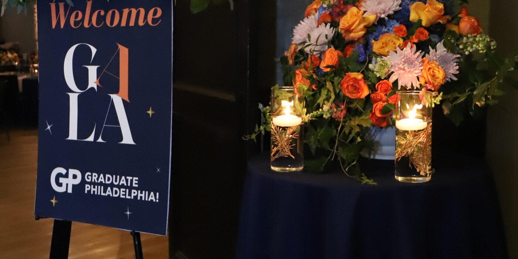 A welcome sign and flowers in front of a table.