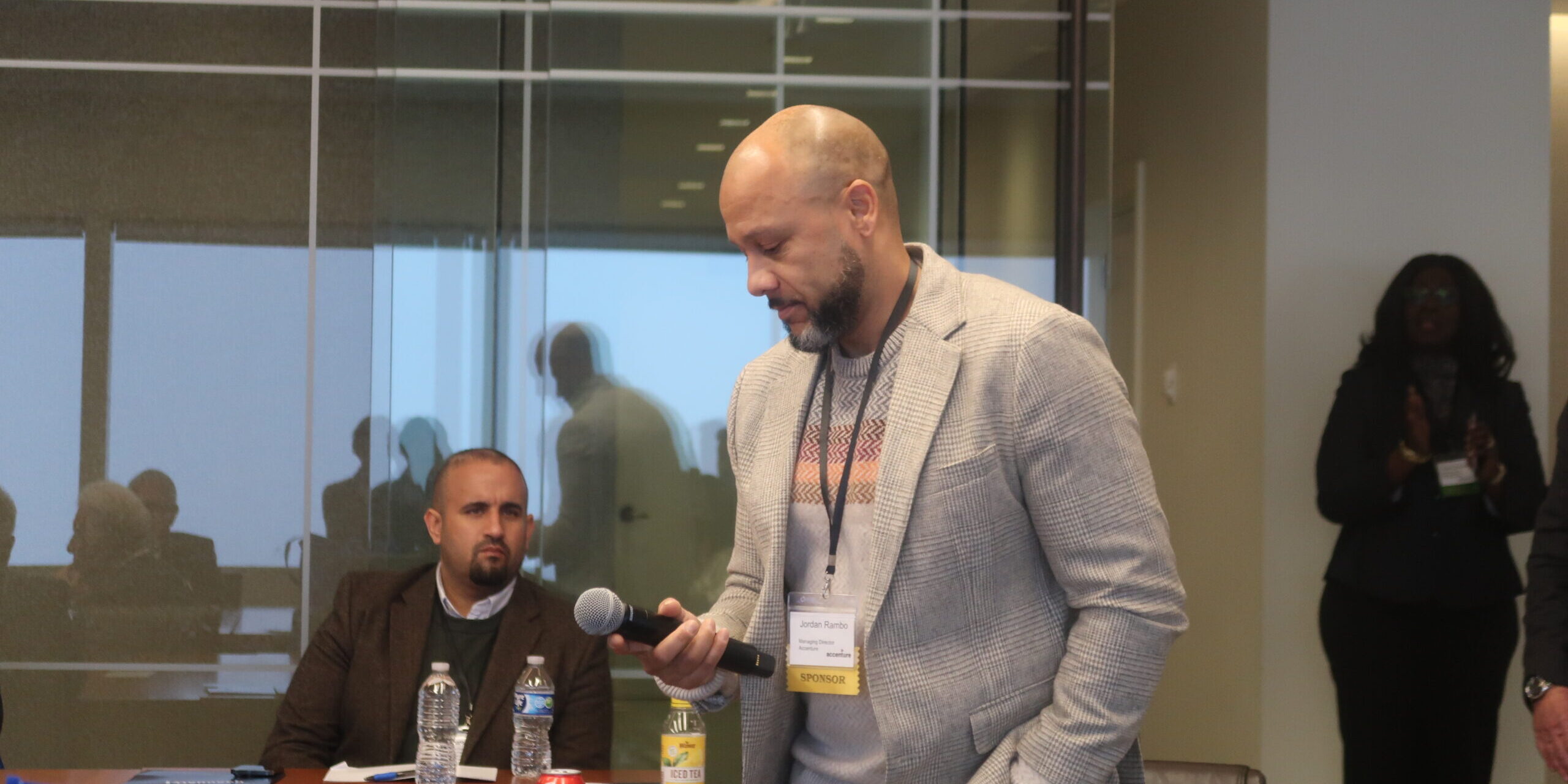 A man standing at a table holding a microphone.