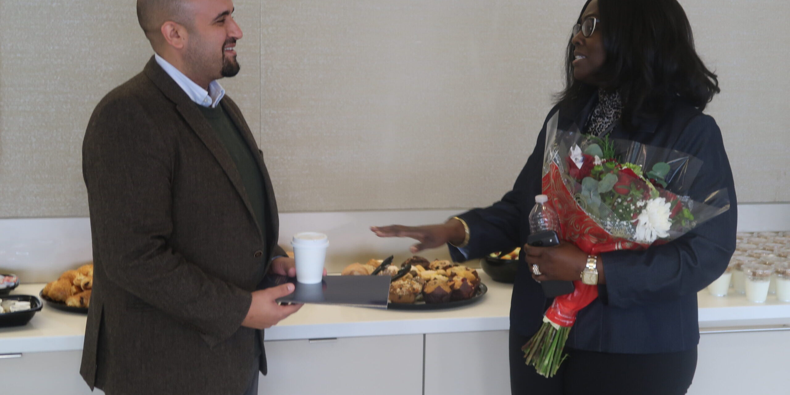 Two people standing in front of a table with food.